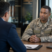 a veteran in uniform speaking to a man in a suit about veteran employment programs.