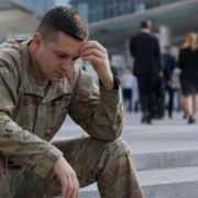 distressed soldier in camouflage uniform, hand on forehead, contemplating military transition employment barriers.