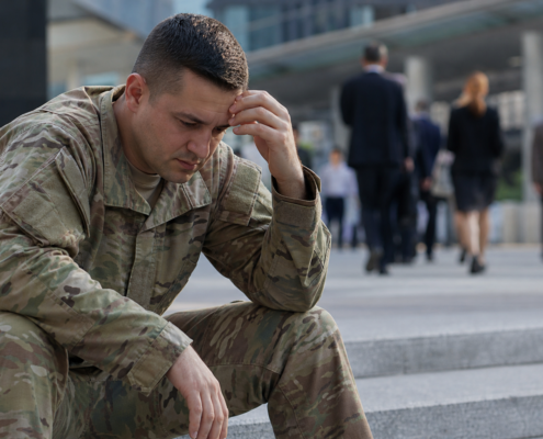 distressed soldier in camouflage uniform, hand on forehead, contemplating military transition employment barriers.