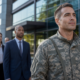 veteran in camouflage looking forward with business professionals, suggesting veteran employment programs