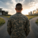back of a veteran in camouflage at a diverging path, one to ruins, one to a city, symbolizing military employment gap veterans face.